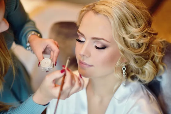 Makeup artist applying bridal makeup on the morning of a wedding.
