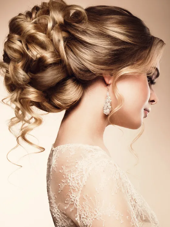 Bride in profile wearing a soft curled updo with loose face-framing pieces.