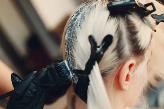 Stylist working colour through a client's hair at the salon.
