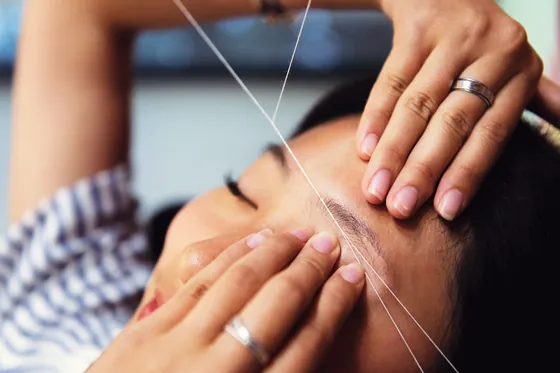 Eyebrow threading being carried out on a client.